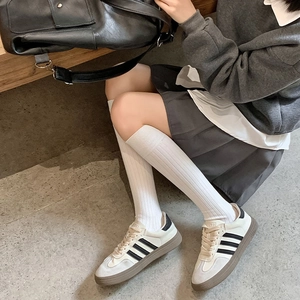 Chaussettes montantes blanches rétro portées avec des baskets à rayures noires