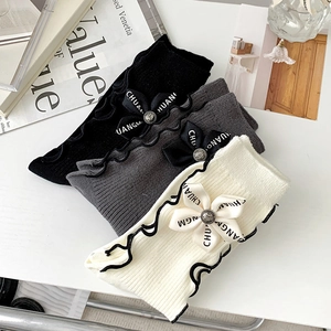 Detail of knit socks featuring wavy edges and decorative bow with vintage metal buttons