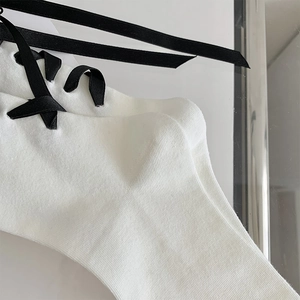 Détail de chaussettes blanches en maille côtelée avec laçage élégant en ruban noir