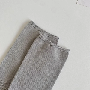 Detail of light gray knitted over-the-knee socks showing ribbed cuffs and vertical texture
