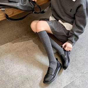 Gros plan de mocassins noirs classiques avec des chaussettes montantes grises à côtes