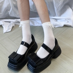 Scarpe Mary Jane nere con plateau e fiocco abbinate a calze a rete bianche