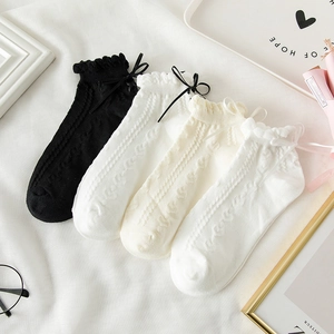 Dettaglio dei polsini con volant e fiocchi sulle calze a righe in stile Lolita