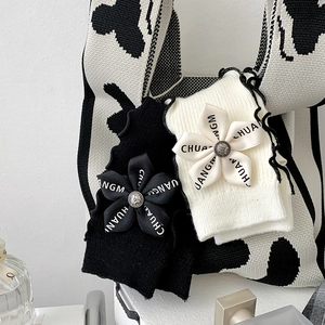 Detailed shot of knit arm warmers with ribbon flowers, metal buttons and ruffled edges