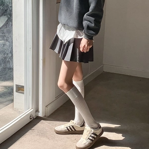 Vue détaillée de chaussettes hautes blanches à rayures avec une jupe plissée