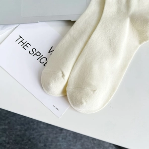 Close-up of knit fabric and reinforced toe seams on cream mid-calf cotton socks