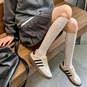 Chaussettes hautes blanches à rayures verticales portées avec des baskets sur un banc
