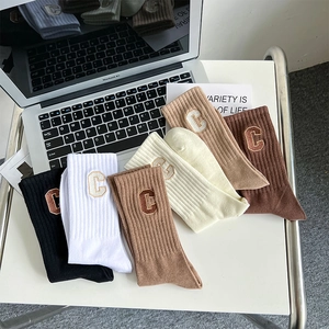 Detailed view of five colors of ribbed cotton socks with embroidered C letter branding