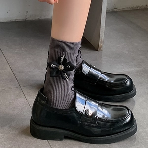 Dark grey bow ribbed socks with floral trim paired with black patent leather loafers