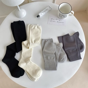Detailed knit texture of ribbed over-the-knee socks in black, white, and grey colors