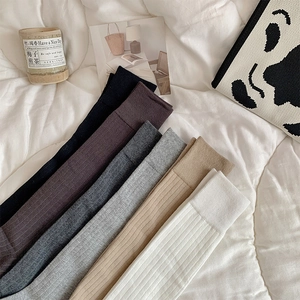 Détail de six paires de chaussettes hautes en maille côtelée de couleurs variées sur un lit