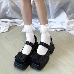 Détail de chaussettes à nœud en dentelle blanche avec babies noires à semelles compensées