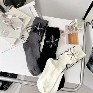 Detail of ribbed cotton socks with floral bow accents and elegant ruffled cuffs