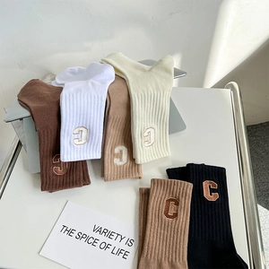 Close-up of ribbed knit mid-calf socks with thick letter C embroidery in various colors