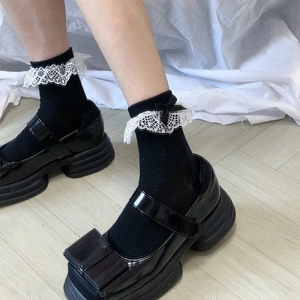 Détail de chaussettes Lolita avec dentelle blanche et nœud noir sur chaussures vernies