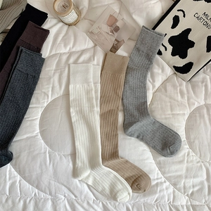 Chaussettes hautes en maille côtelée de couleurs variées posées sur un lit blanc