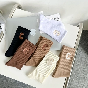 Close-up of ribbed cotton mid-calf socks with embroidered C letter in earth tones