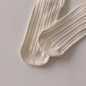 Macro detail of creamy white ribbed cotton knit fabric on sweet style baby mid-calf socks