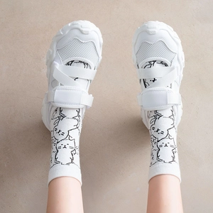 Close-up of white crew socks with cartoon cat prints and chunky velcro sneakers