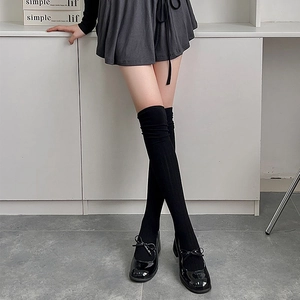 Detail of black over-the-knee socks with vertical ribbed knit and elastic texture