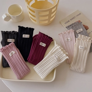 Detail of ruffled cotton crew socks in multiple colors with woven labels on a white tray