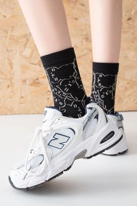 Close-up of black cotton mid-tube socks with cute white cat print and white sneakers