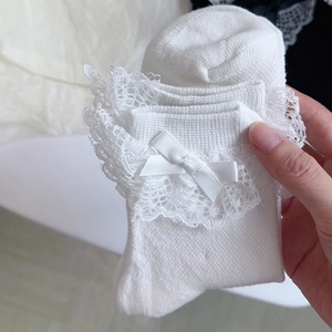 Détail de chaussettes Lolita blanches avec dentelle délicate et nœuds en satin