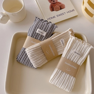 Three pairs of ribbed knit cotton socks in grey, beige and off-white with brand tags