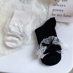 Détail de chaussettes Lolita en tricot avec dentelle délicate et nœuds en noir et blanc