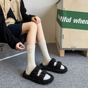 Detail shot of black faux shearling double-strap sandals with metal buckles