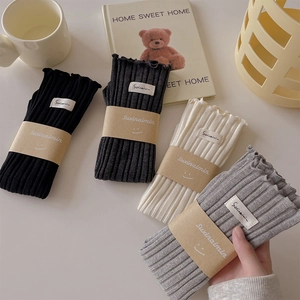 Close-up of four colors of ribbed cotton socks with ruffle edges and brand labels