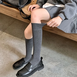 Détail de chaussettes hautes gris foncé montrant la maille côtelée et la texture du coton