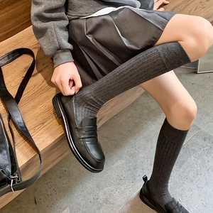 Détail de chaussettes mi-mollet en maille côtelée gris foncé avec mocassins noirs