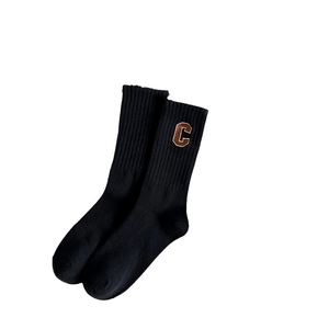Classic black mid-calf cotton socks with vertical ribbed texture and brown letter C patch