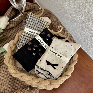 Vue détaillée de chaussettes à fleurs et à carreaux avec nœuds dans un panier tressé