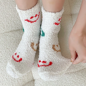 Detailed view of stretchy white coral fleece socks with colorful embroidered smiley faces
