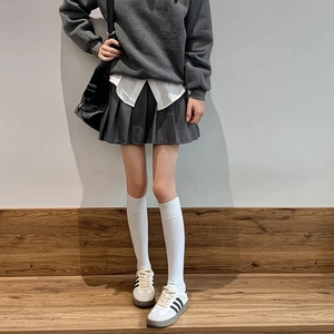 Détail de chaussettes hautes blanches avec une jupe plissée et des baskets de style