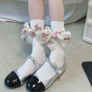 Dettaglio calze bianche in cotone con grandi fiocchi in pizzo e chiffon floreale