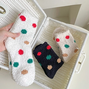 Soft coral fleece socks with colorful polka dots in a white basket for winter warmth