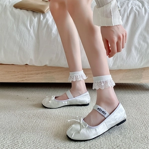 Detailed close-up of white lace socks paired with branded bow ballet flat shoes