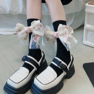 Dettaglio di calze Lolita in pizzo con grandi fiocchi ricamati a rose e scarpe Mary Jane