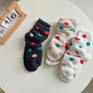 Detail of three pairs of thick coral fleece socks with colorful polka dots on a table