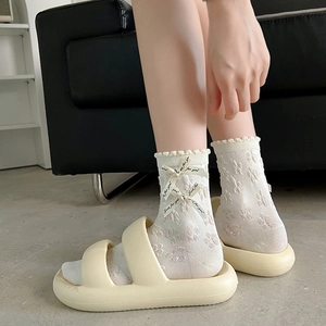 Détails de chaussettes blanches à volants avec nœud et sandales à semelles compensées