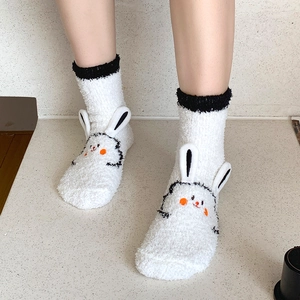 Detailed close-up of fluffy white coral fleece socks featuring 3D cartoon bunny ears