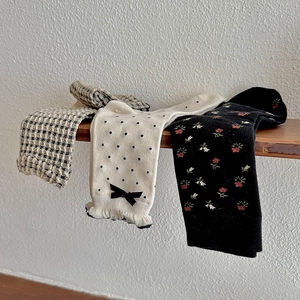 Trois paires de chaussettes à fleurs et pois avec bords festonnés sur une étagère