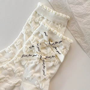Détail de chaussettes blanc crème avec textures florales et nœuds Just for you