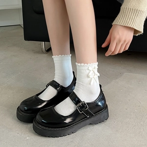 Dettaglio di calze bianche in pizzo Lolita con fiocco e scarpe Mary Jane nere con zeppa