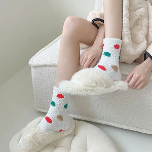 Close-up of coral fleece polka dot socks paired with white plush slippers for home comfort