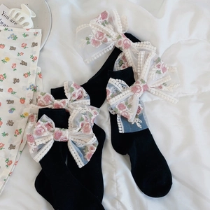 Dettaglio calze Lolita nere con grandi fiocchi in pizzo bianco e ricami floreali rosa
