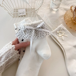Dettaglio di calzini bianchi Lolita con balze in pizzo e fiocchi neri a pois raffinati